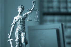 Metallic statue of Lady Justice holding scales and sword, blindfolded to symbolize impartiality—set against a modern office backdrop, representing BankCardLaw’s commitment to fair, decisive legal advocacy